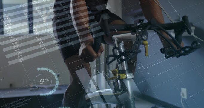 Fototapeta Pedaling cyclist wearing jersey on exercise bike in gym by window blinds, with performance overlays