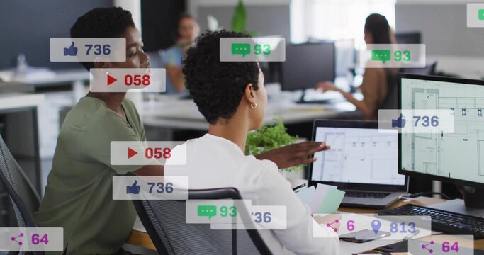 Pointing woman in white blouse showing laptop screen in open-plan office, with social media metrics - Powered by Adobe