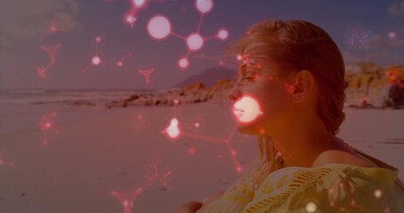 Sitting woman in top hugging knees at shore, wireless earbuds, red network overlay, copy space