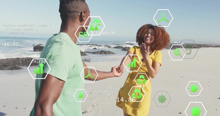Couple holding hands walking along beach wearing tee and dress, with AR icons showing charts code