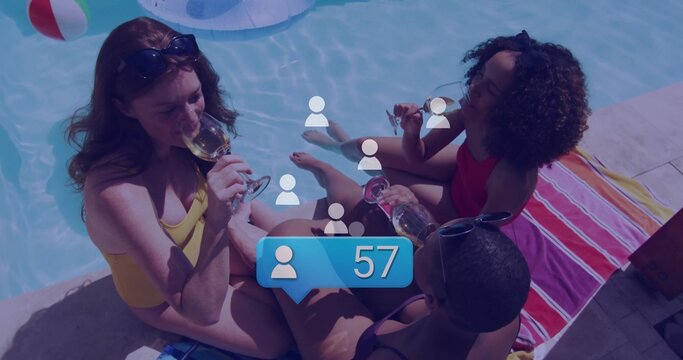 Sipping wine three women in swimsuits sitting at backyard pool with beach ball and champagne flutes - Powered by Adobe