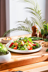 Gourmet salad with lettuce, strawberry, shrimps and walnuts on table in bright modern kitchen