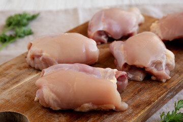Raw Organic Boneless Skinless Chicken Thighs on a Wooden Board, side view. Close-up.