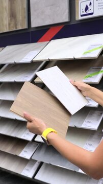 Hands holding ceramic tiles in hardware store comparing options for renovation