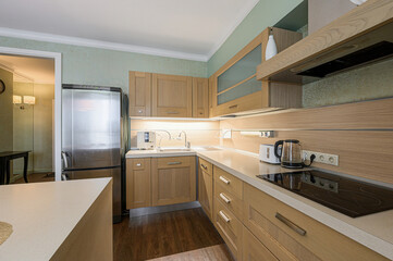 well-lit kitchen with light wood cabinets, stainless steel refrigerator, and modern appliances. Warm and inviting space