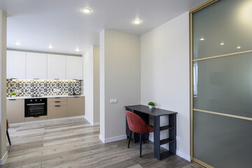 modern apartment interior featuring a kitchen, dining area with a desk, chair, and a sliding door closet