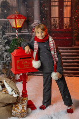 Little child, preschool boy, sending letter to santa in christmas mailbox, christmas decoration around him, outdoor snow shot