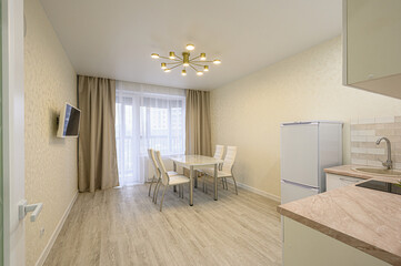 bright, modern apartment interior.  A dining table and chairs sit near a window, with kitchen elements visible