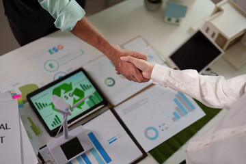 Top view of professionals shaking hands over ESG reports in a modern office.