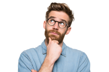 Thoughtful young man with beard and glasses in denim shirt looking up with hand on chin, isolated on white background
