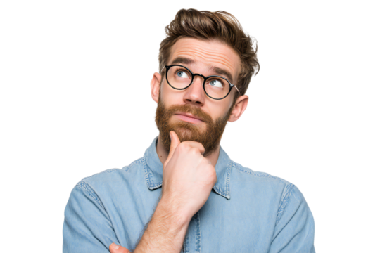 Thoughtful young man with beard and glasses in denim shirt looking up with hand on chin, isolated on white background