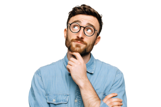 Thoughtful young man with beard and glasses in denim shirt looking up with hand on chin, isolated on white background
