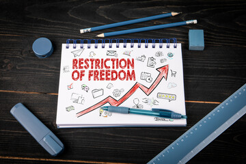 Notebook with text Restriction Of Freedom and upward arrow surrounded by business icons....