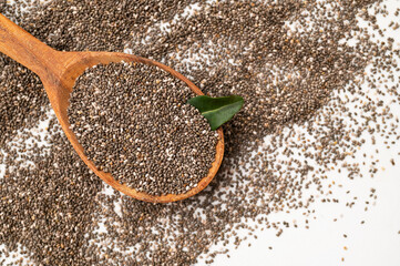 Chia seeds in wooden spoon on light gray background flat lay top view. Food background, healthy eating concept, superfood. Dry organic chia seeds rich in omega-3, protein, vitamins and minerals