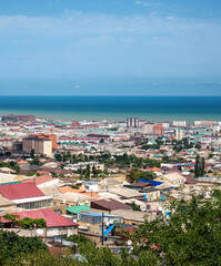 Obraz premium Coastal city with mix of colorful roofs and mid-rise buildings, natural daylight, sea in the background