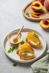 Toast bruschetta with peach, nectarine, cream cheese or ricotta and honey on a plate on a light background