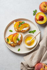 Flat lay of toast bruschetta with peach, nectarine, cream cheese or ricotta and honey on a plate