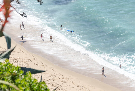 Beachgoers and surfers on golden sand shoreline, Sintra coast