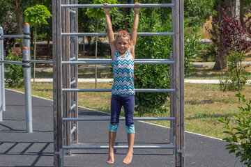 Obraz premium Child hanging on outdoor wall bars at a playground