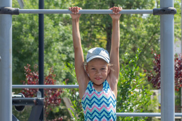 Obraz premium Girl Hanging on Horizontal Bar at Playground