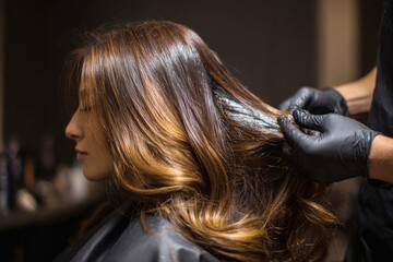 Hairdresser dyes woman's hair professionally in a hair salon