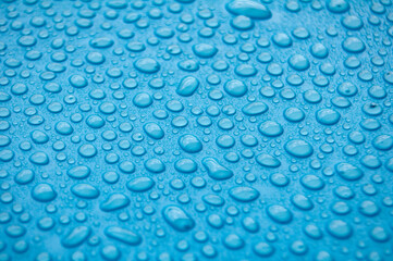 Deep bluish-purple textured surface with evenly distributed water droplets in close up view.