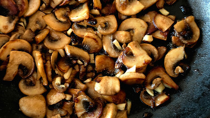 Close-up of sautÃ©ed mushrooms and garlic in a frying pan, golden and aromatic.