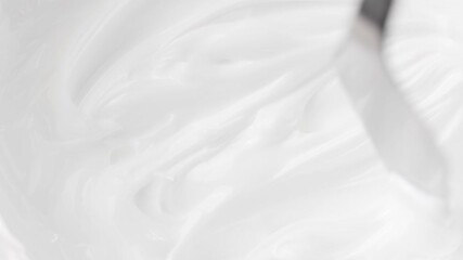 Top-down view of metal spatula smearing white cream. Rotating texture of facial or body cosmetic mask. Perfect for skincare and beauty content. - Powered by Adobe