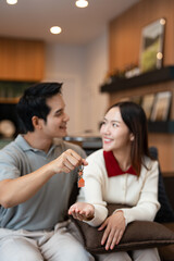 Homeowners. Happy young asian couple  wife and husband holding house flat apartment keys, celebrating new purchase buying real estate . Mortgage loan.