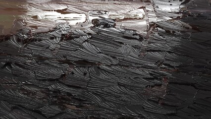 Close up of abstract black oil paint texture with glossy strokes and reflective highlights
