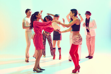 Fototapeta premium Stylish friends dancing together in retro themed group celebration. Concept of dance parties, youth culture, nightlife entertainment and lifestyle fun.
