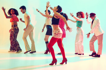 Retro styled group dancing with joyful energy under colorful lights. Concept of music promo, youth lifestyle, dance parties and cultural celebration.