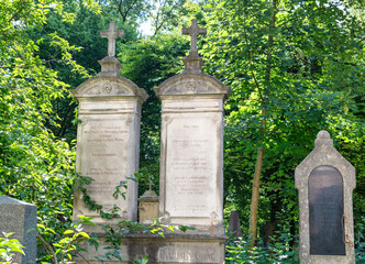 Zwei gleiche Grabsteine nebeneinander  inmitten von Büschen und Bäumen  Alter Südfriedhof München