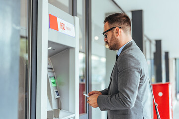 Businessman Using ATM Machine for Banking Transaction Outdoors