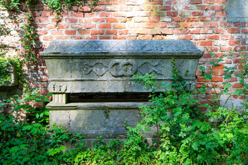 sehr alte Grabstätte in Form eines Sarges vor eine Ziegelmauer Alter Südfriedhof München