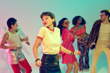 Fototapeta premium Playful young woman dancing with retro fashion group at party. Concept of fun, lifestyle entertainment, youth creativity and cultural celebration.