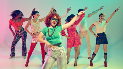 Woman in green shirt leading retro dance group under neon spotlight. Concept of confidence, performance, nightlife energy, disco revival and music-driven celebration.