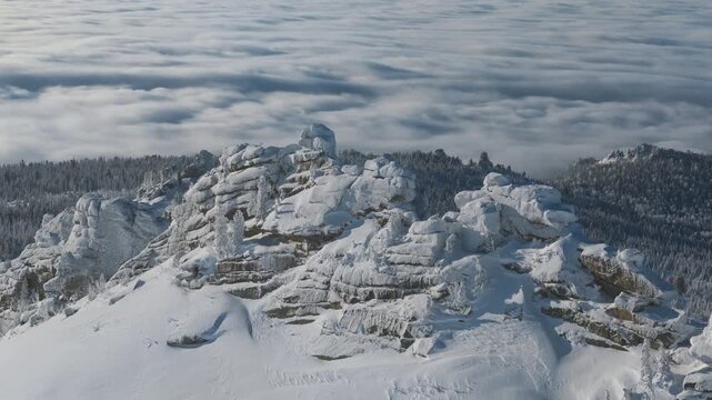 Aerial view of a granite tower above a cloud sea at Sheregesh in Mountain Shoria. Frosted slabs and pine rise from inversion as light sculpts form, ideal for tourism, adventure and nature branding