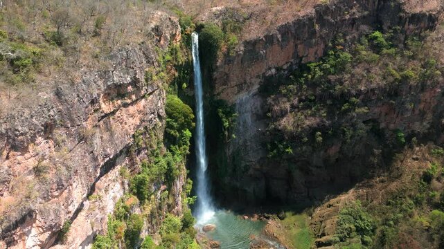 Cachoeira imponente caindo em meio a um c&acirc;nion de pared&otilde;es rochosos, com vegeta&ccedil;&atilde;o esparsa e tons terrosos predominantes.