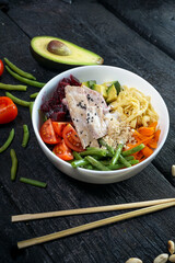 bipimbap with meat in a white plate on a dark background with avocado