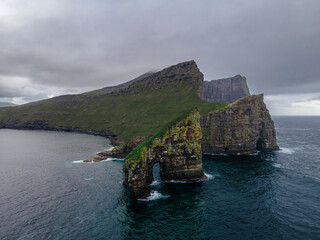 Fototapeta premium Drone view of Drangarnir cliff with Tindholmur islands in the background during early morning hike