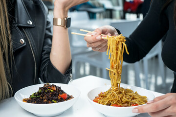 girl eating noodles with chopsticks over a white plate vertical photo