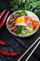 bibimbap with sprouts and egg in a white plate on a dark background
