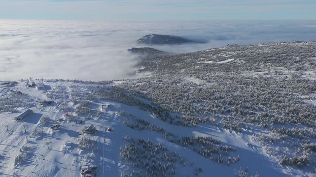 Cloud inversion covers the Sheregesh summit as buildings and pylons sit among frosted taiga. A wide view reveals piste layout and mountain setting, useful for masterplan, tourism and destination use