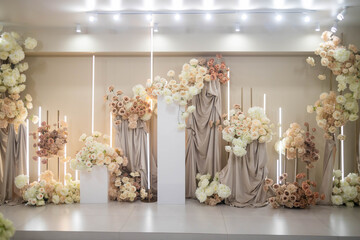 Wedding arch at the restaurant. Round flower arch. Trend in the wedding banquet room is a white arch decorated with flowers and greens, in the background white wall.