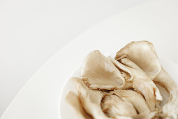 Fresh oyster mushrooms filling a white plate, ready for cooking
