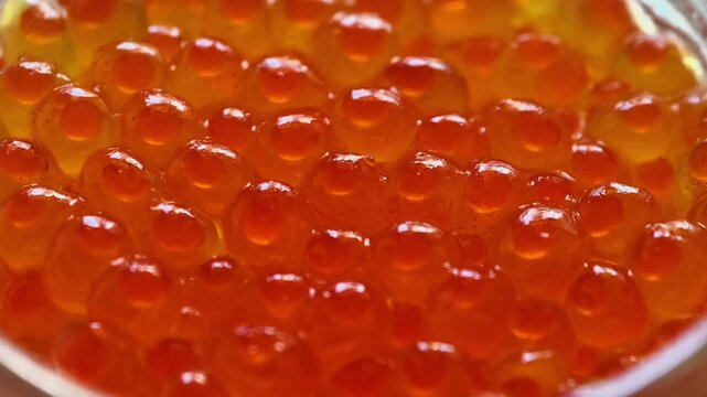 A closeup view of vibrant and glossy salmon roe, showcasing its rich orange color and smooth texture to behold