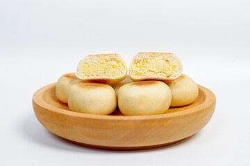Close up view of delicious Bakpia, round pastry filled with sweet green bean paste, a specialty traditional snack from Yogyakarta, Indonesia. Bakpia on a wooden plate Isolated on white background.