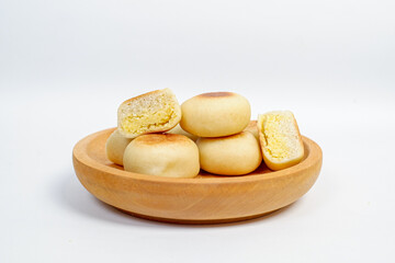 Close up view of delicious Bakpia, round pastry filled with sweet green bean paste, a specialty traditional snack from Yogyakarta, Indonesia. Bakpia on a wooden plate Isolated on white background.