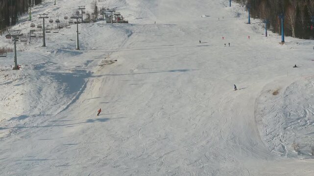 Aerial view of a wide groomed piste in Sheregesh framed by lift towers and sparse riders on firm snow. Long shadows, crisp air and open space make an ideal Siberian setting for tourism and training